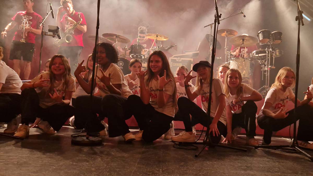 Foto von Singin‘ IDA! – der Kinderchor in Hamburg, bei einem der Meilensteine, auf der Bühne der Markhalle zusammen mit Le Fly