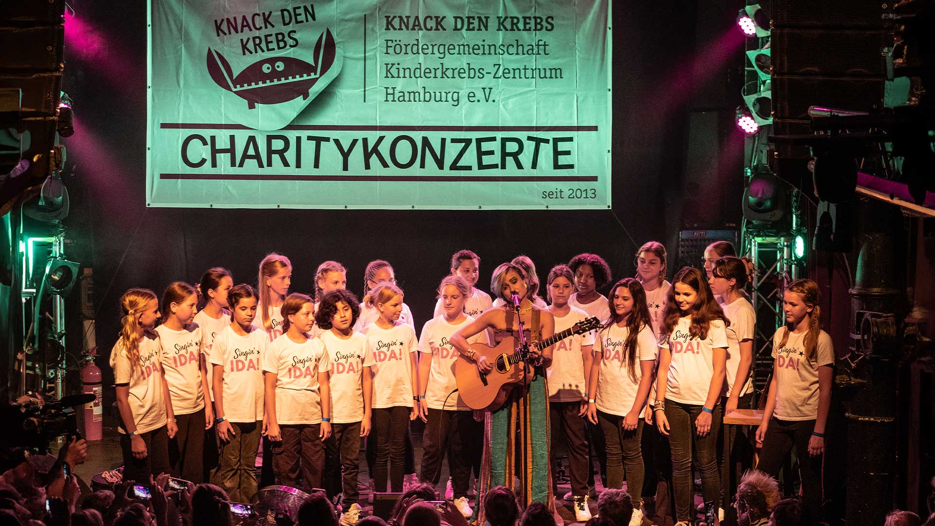 Ein Live-Foto von Singin‘ IDA! – der Kinderchor in Hamburg, auf der Bühne für soziales Engagement bei Knack den Krebs-Charity Konterte